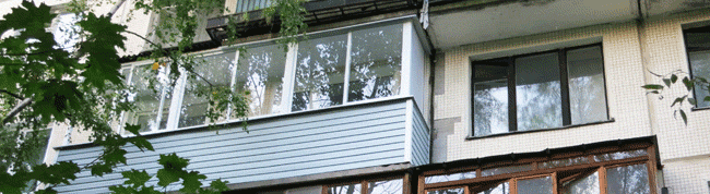 В многоэтажном доме остеклён балкон раздвижными окнами Проведал,  белого цвета. Частично установлена крыша. Обшит снаружи сайдингом.